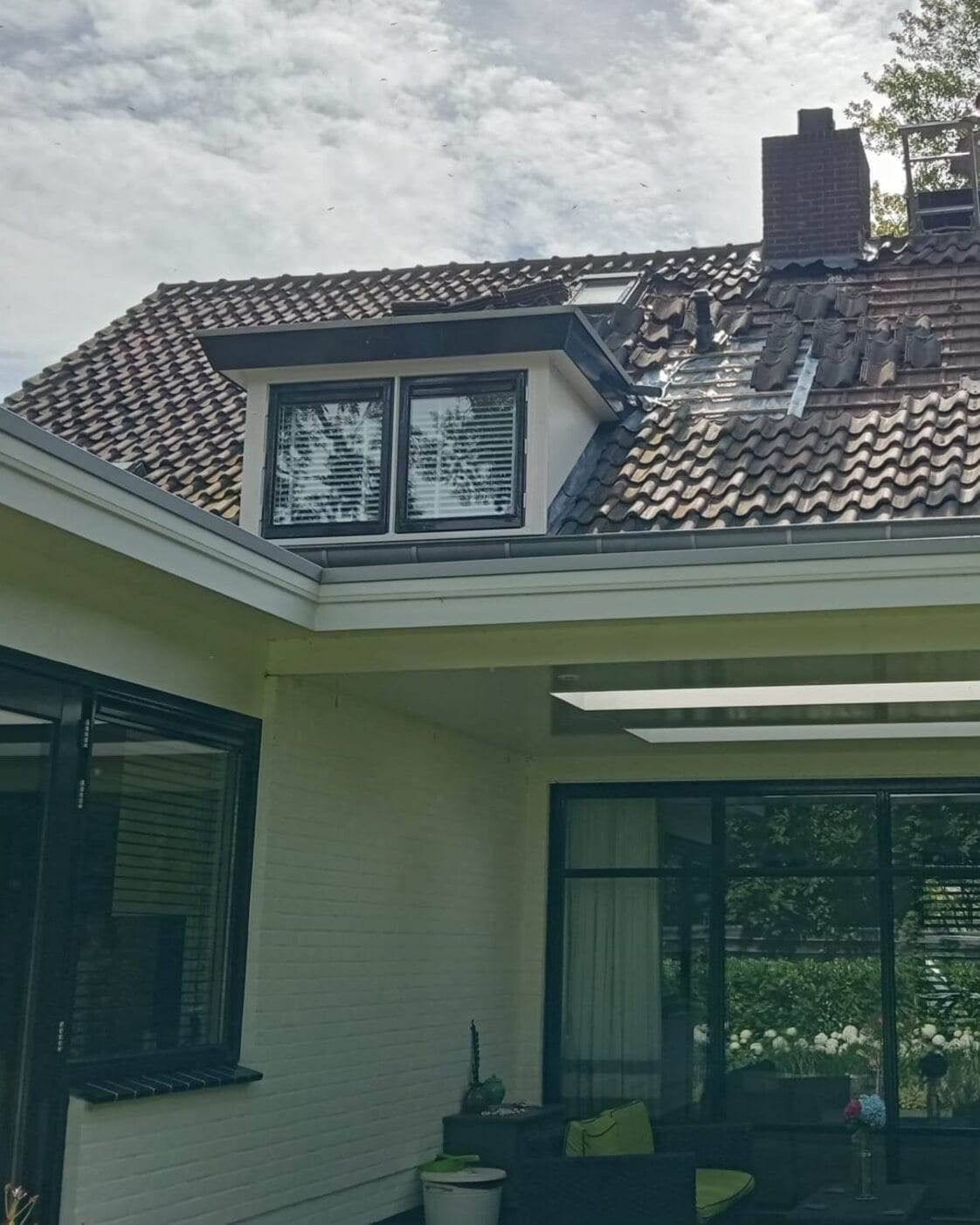 Een dakkapel op een dak waar de nieuwe pannen gelegd worden