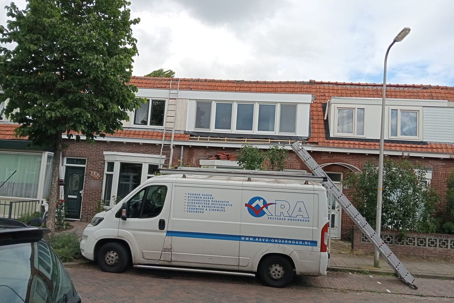 De bus met een ladder tegen de gevel, in een straat met rijtjeshuizen