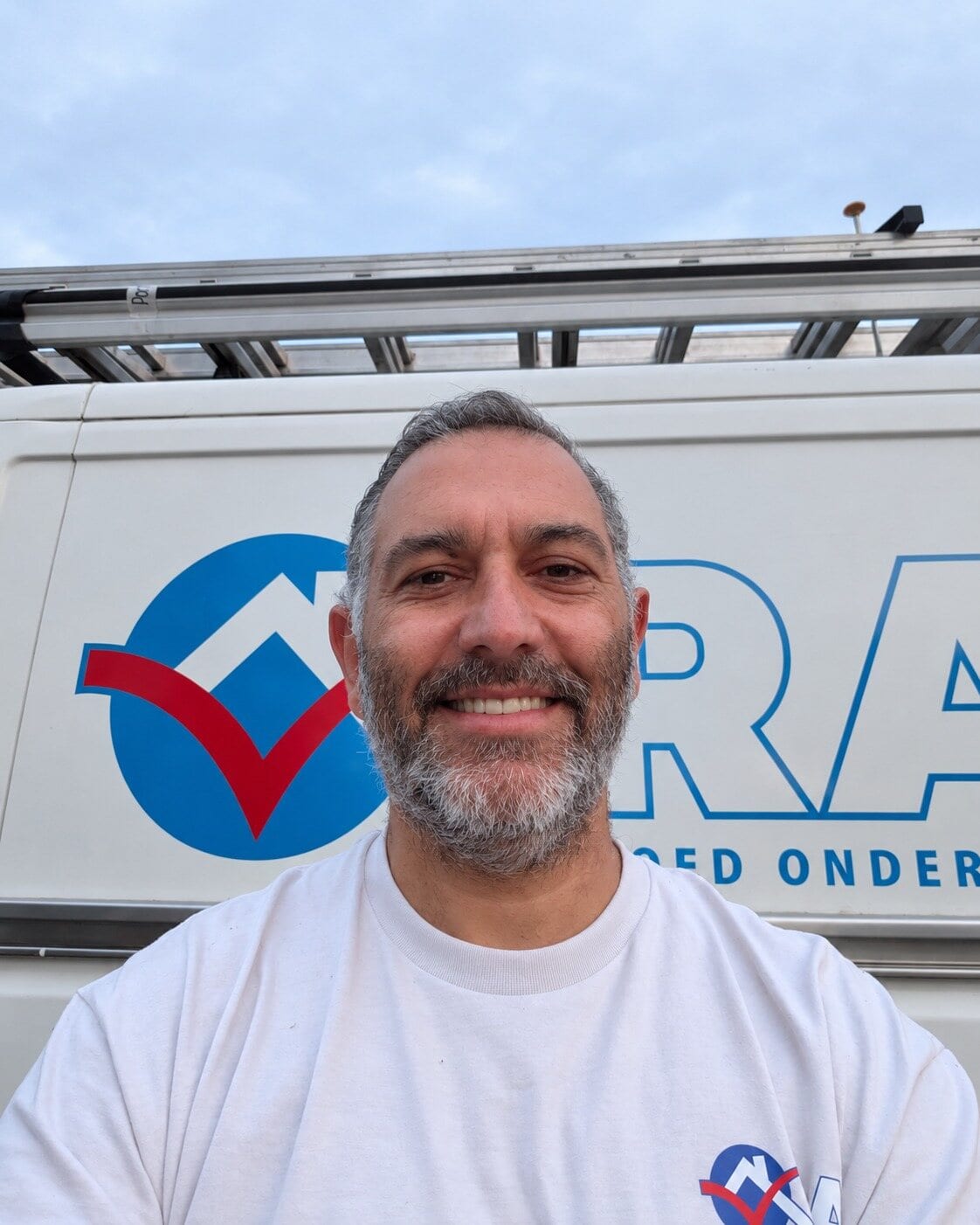 Ramazan, eigenaar van R.A. Vastgoed Onderhoud, glimlachend voor zijn werkbus