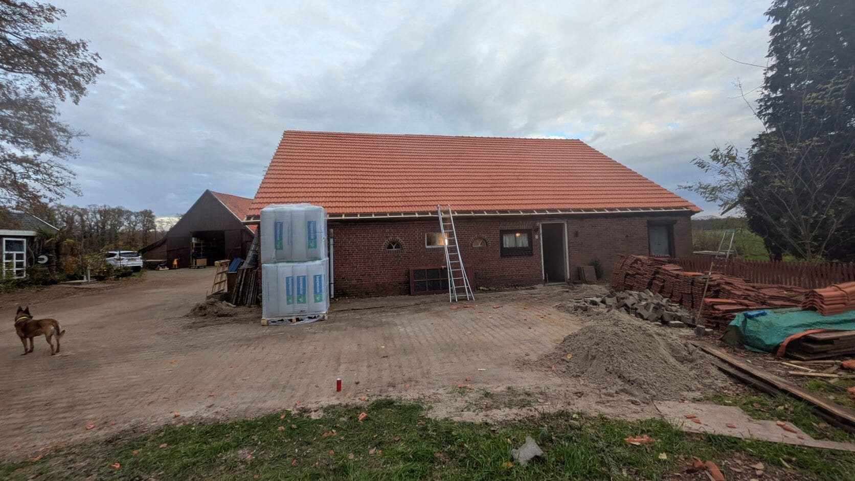 Woonboerderij met nieuwe oranje dakpannen gezien vanaf het erf