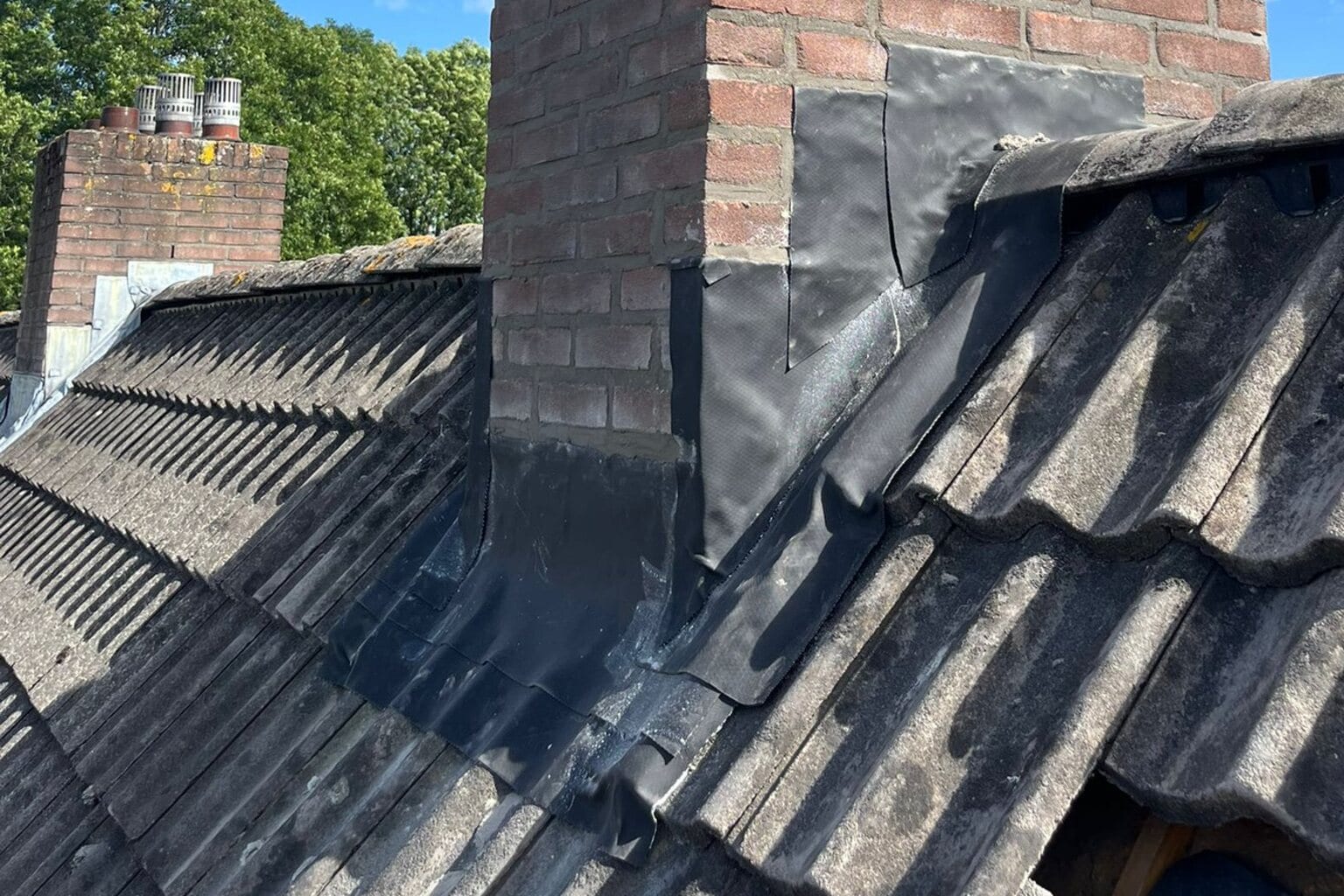 Voor de renovatie: verweerde gemetselde schoorsteen met open dakconstructie